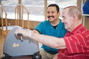 A physical therapist helping a man in the rehab gym