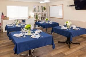 Dining room tables set with flowers and plates at Rock Creek Care Center
